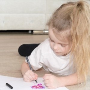 A girl drawing what she is thankful for on paper
