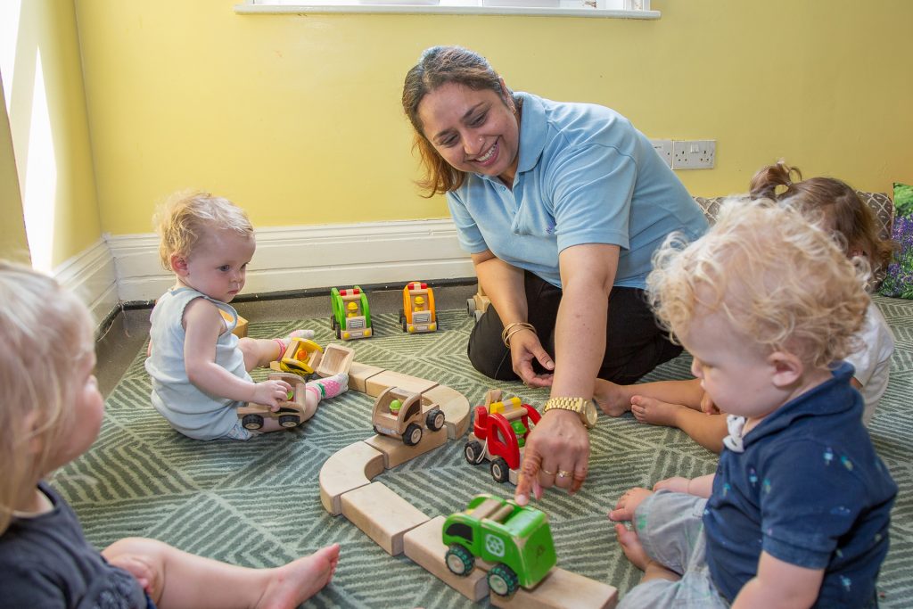 Member of staff looking after children playing with trainset