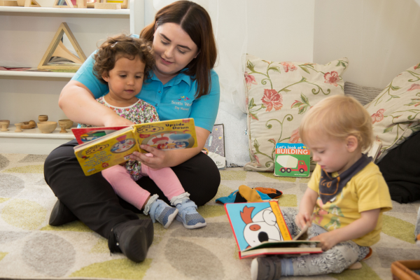 Nursery practitioner reading stories with toddlers 